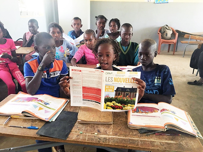 Les enfants de la classe à Sindia en train de lire Les Nouvelles d'Othis (Photo Bonjour Toubab)